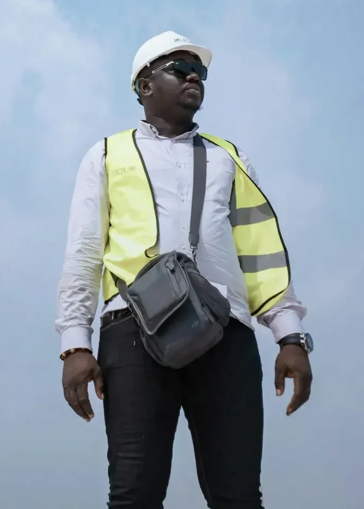 A man wearing a reflective vest and hard hat looks confident against a clear sky.